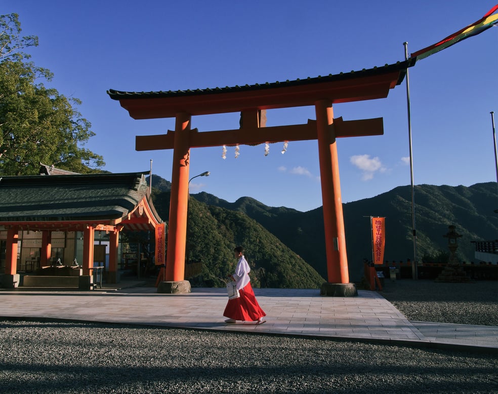 Woman Wearing Red and White Dress walking near a Shinto shrine